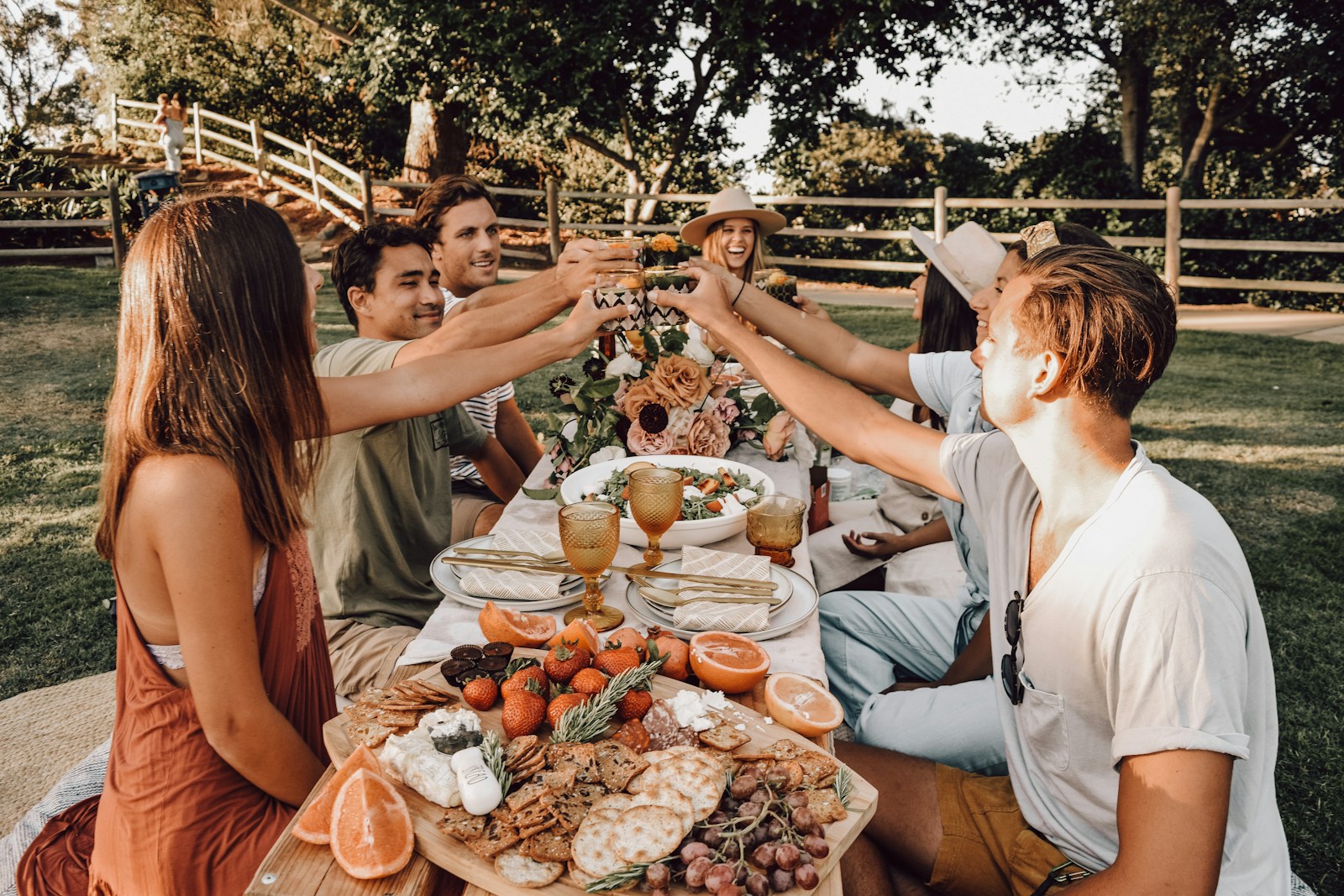 Friends raising a glass over a long outdoor lunch