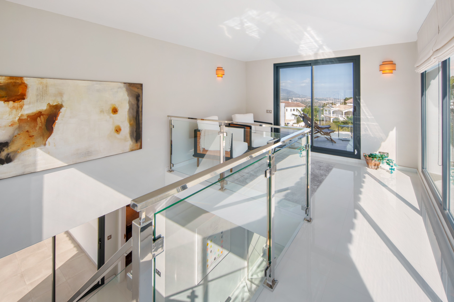 Glass-balustraded landing overlooking the bright entrance hall