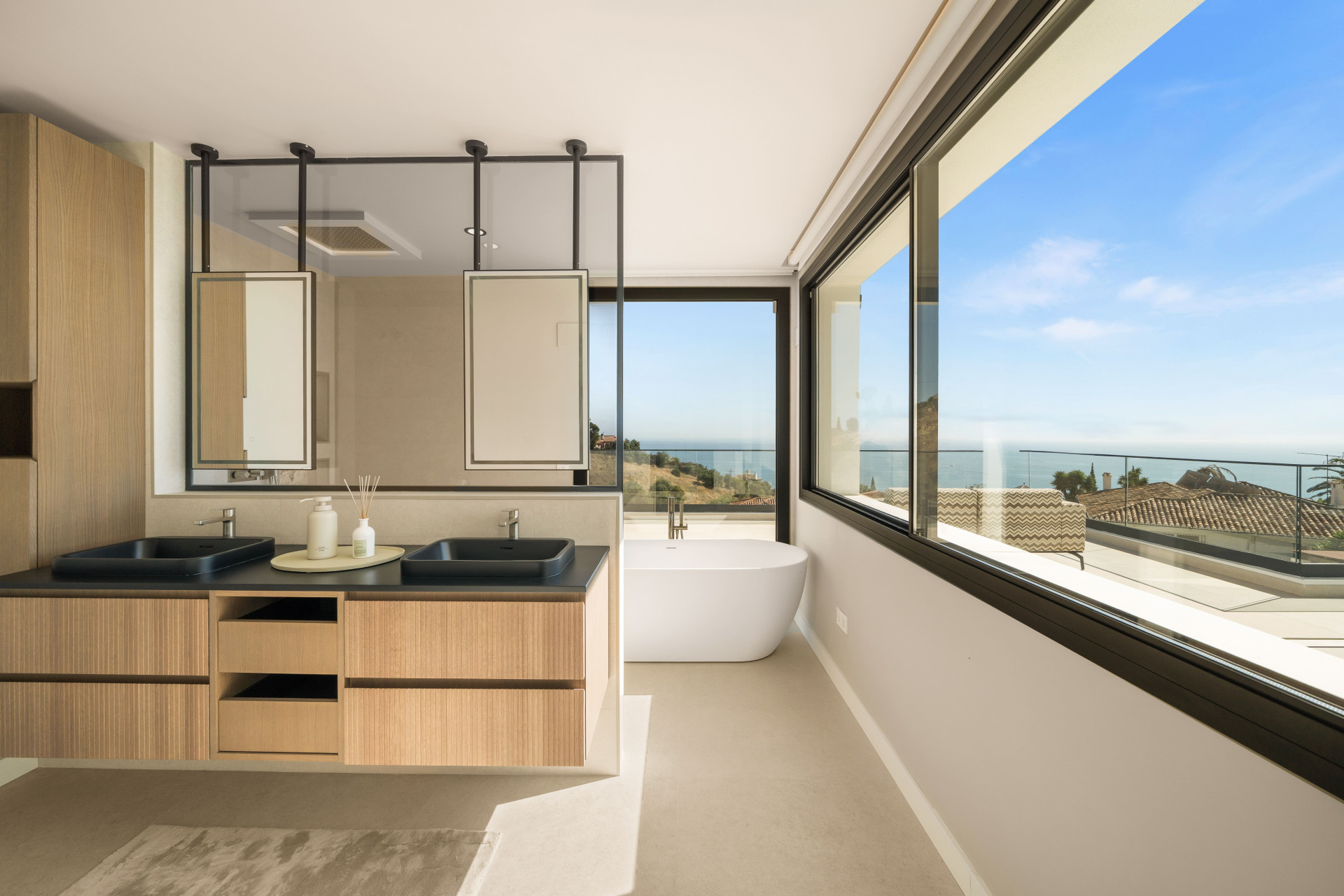 Bathroom with twin basins and a freestanding bath beside wide windows