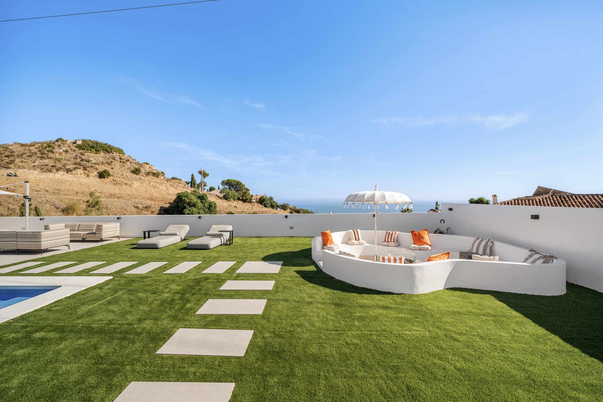 Curved outdoor lounge and fire pit beside the villa garden
