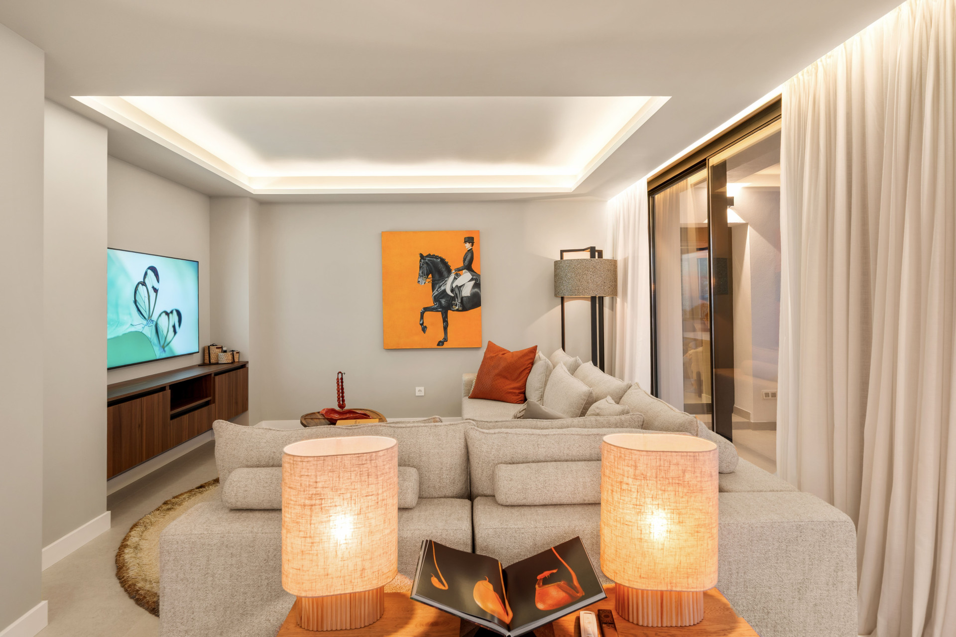 Softly lit living room with pale seating and wide glazing