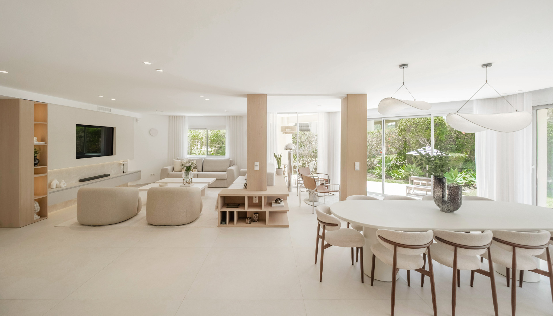Pale curved seating and a dining table beside garden-facing glazing.
