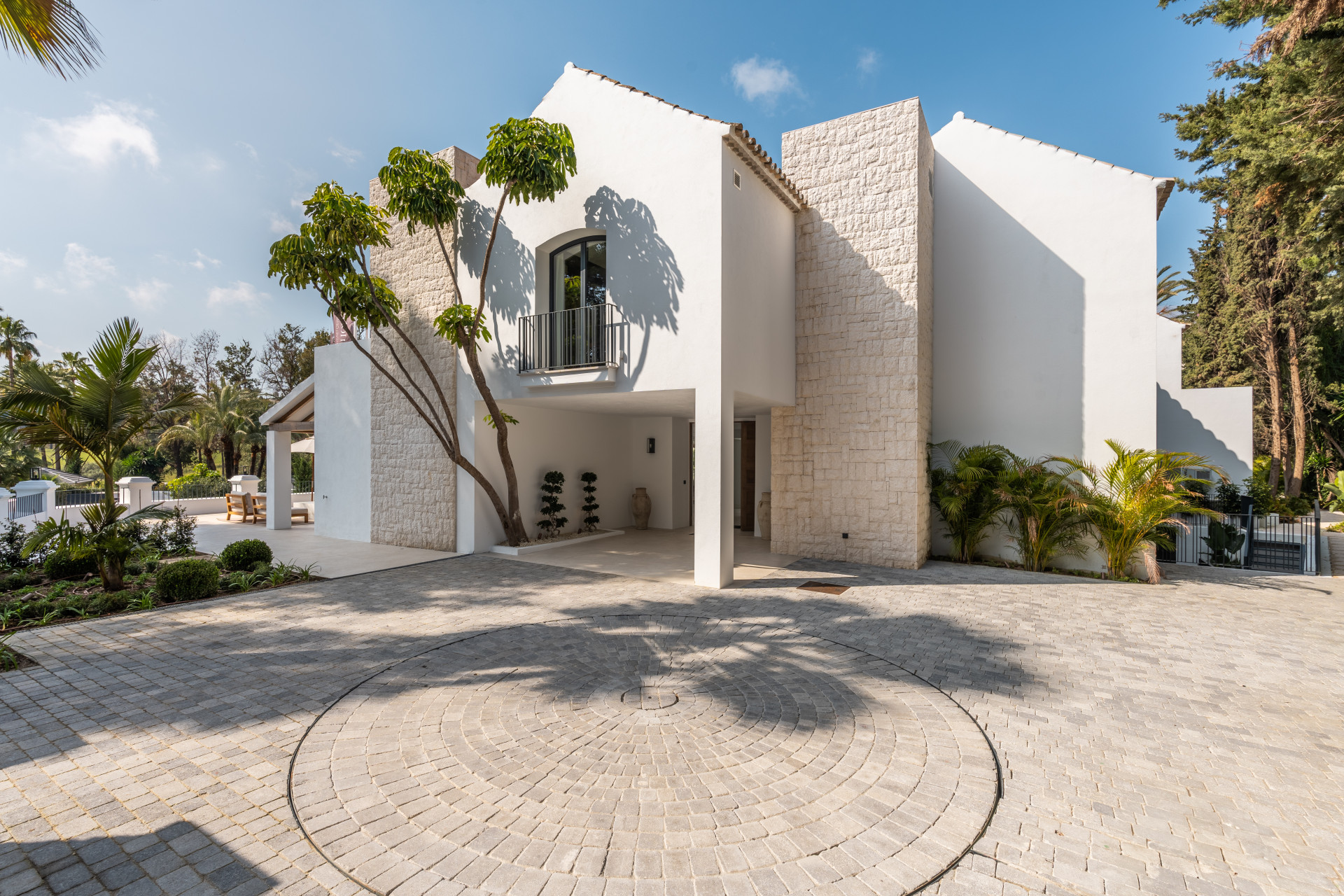 White villa entrance with stone cladding and a circular driveway platform