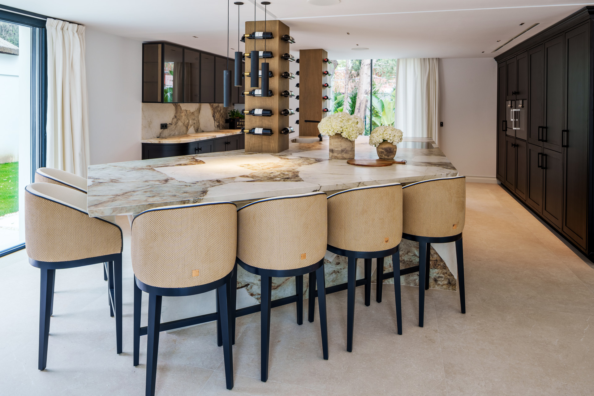 Veined stone kitchen island with seating and dark cabinetry