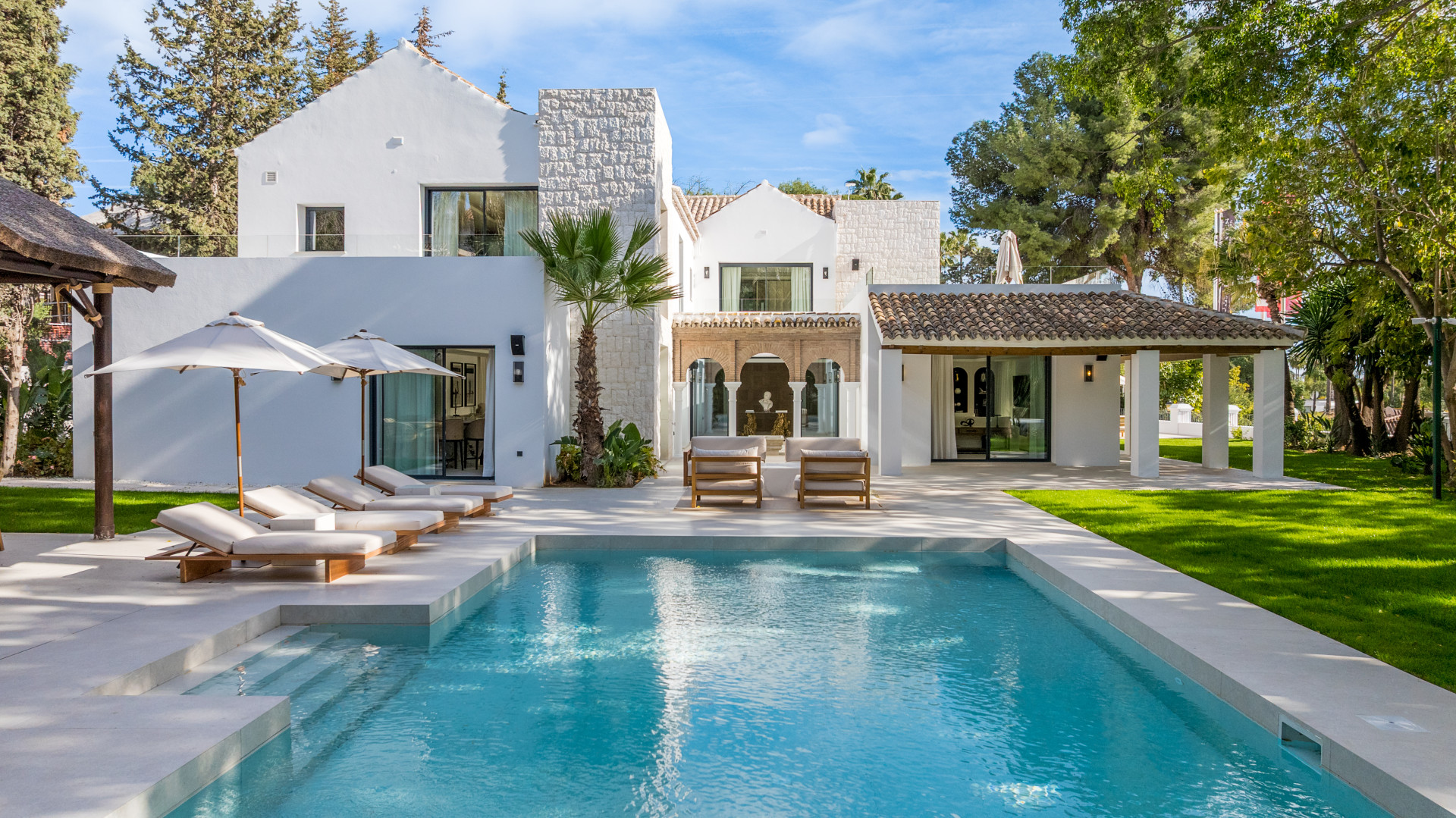 Private pool, lawn and white villa with stone detailing in Las Brisas
