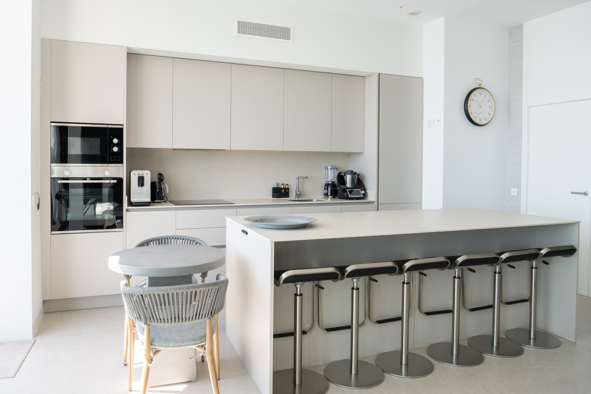 Pale fitted kitchen with breakfast-bar seating and integrated appliances.