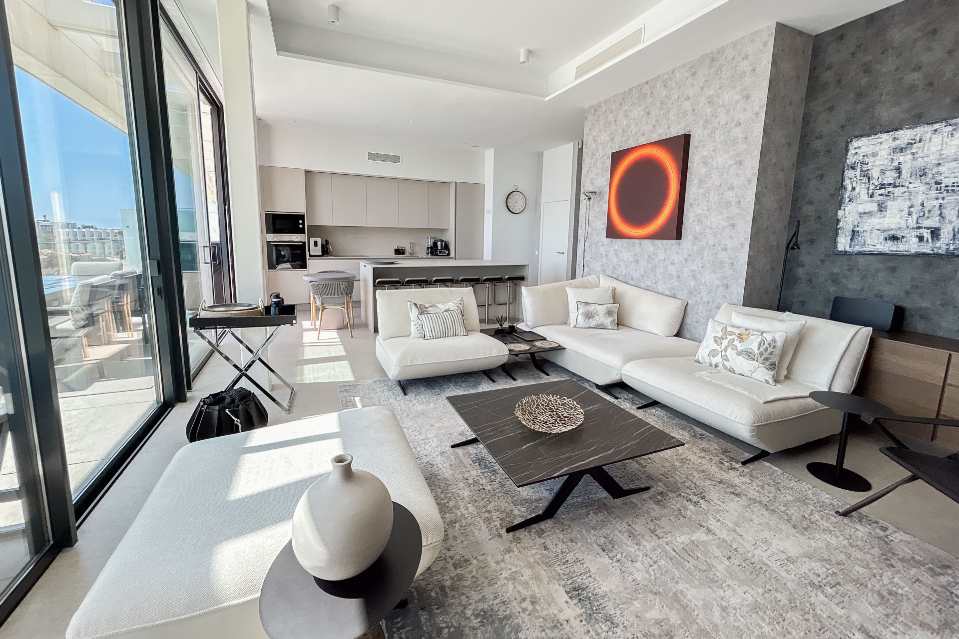 Bright living room with white seating, full-height glazing and an open kitchen at Nereidas.