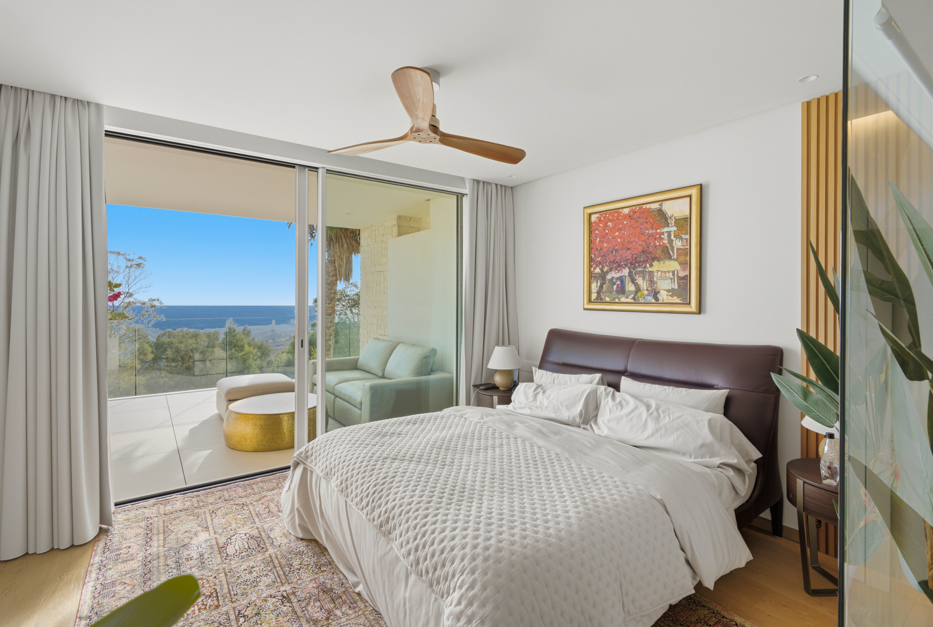 Bedroom with an upholstered headboard and sliding doors opening onto a sea-view terrace.