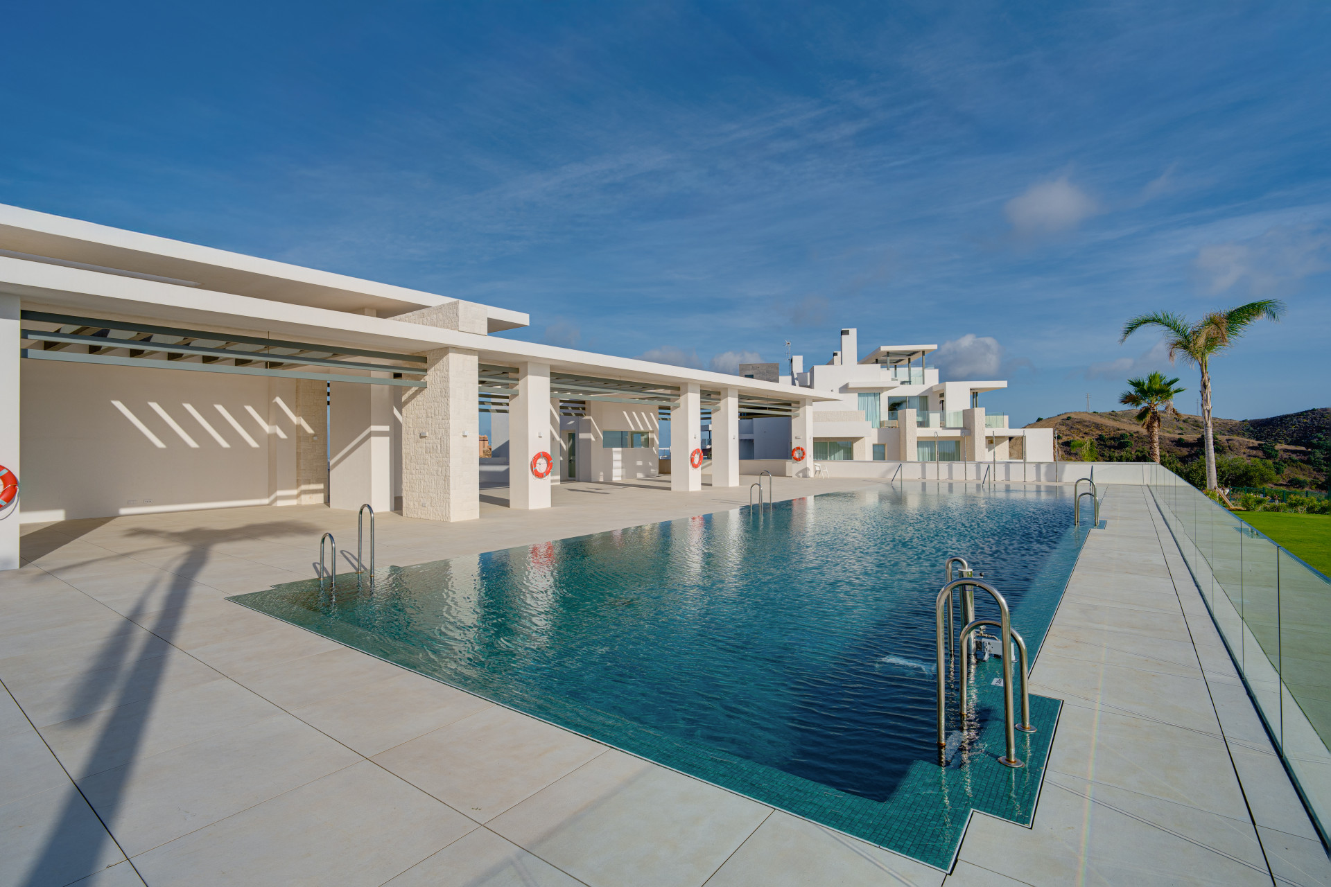 Ocean View communal swimming pool beside pale buildings, a pergola and landscaped lawns.