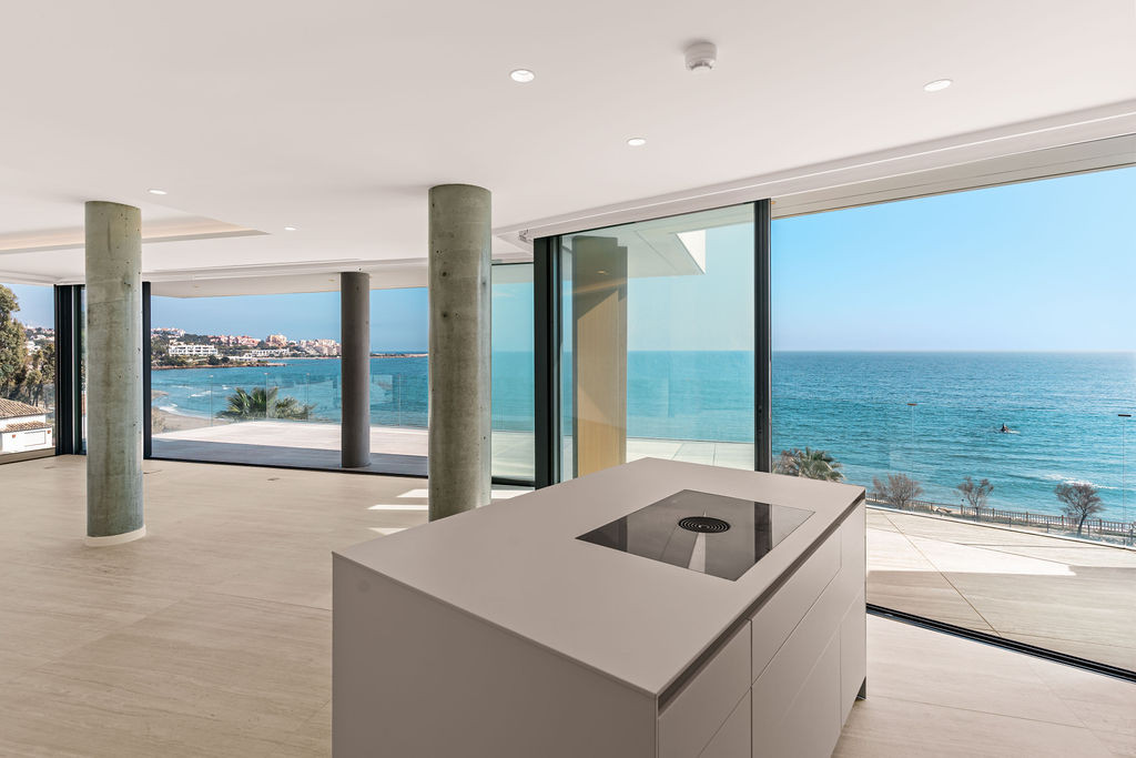 Kitchen island, concrete columns and floor-to-ceiling glazing facing the sea at The Sapphire