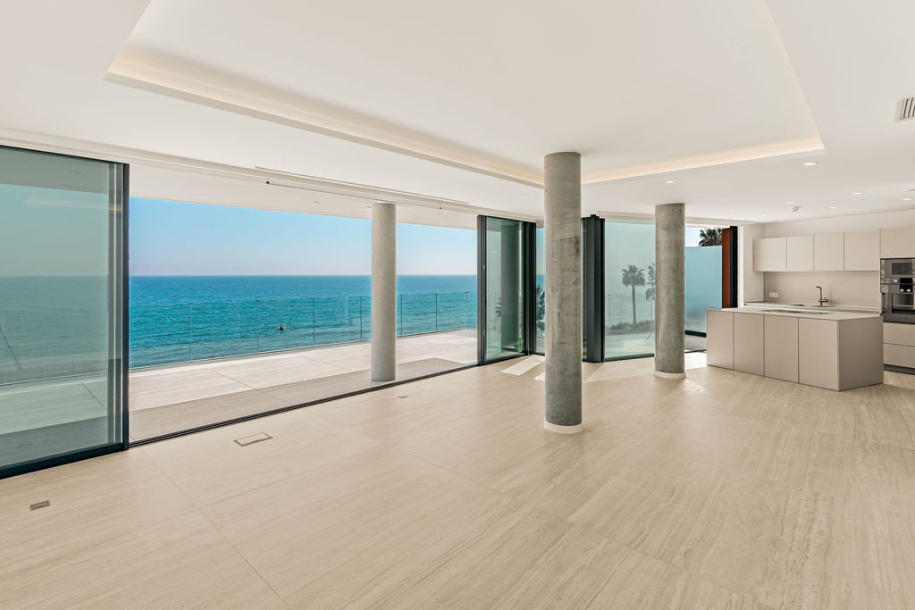 Unfurnished open living room with full-height sliding glass doors and a sea-facing terrace